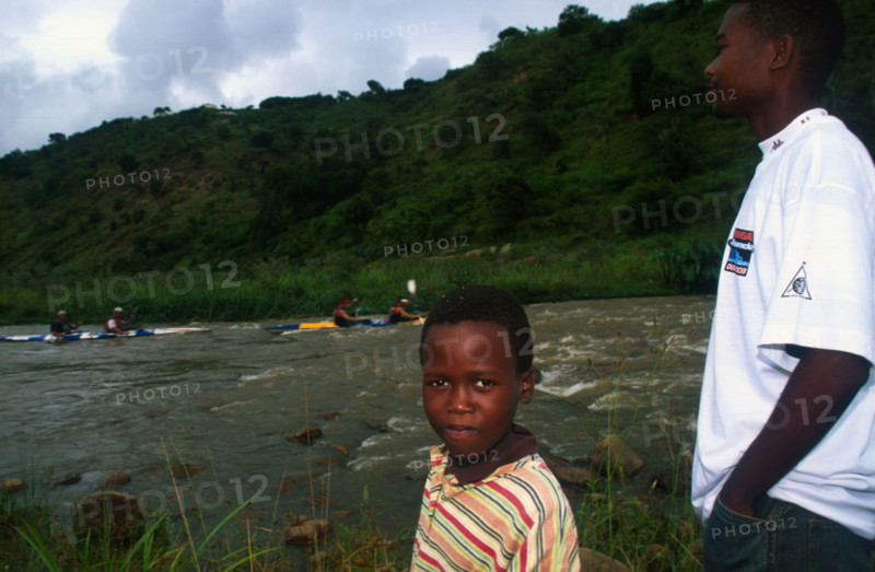 young man and boy in foreground with canoes on river in backgrou