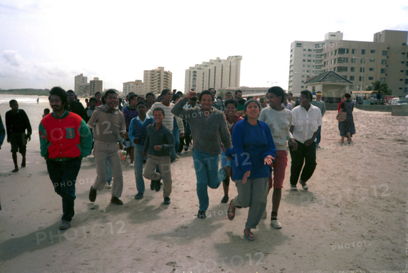 1989, The Strand, Cape Town, South Africa

coloured people, demonstrations against apartheid, beach demonstrations, cars, shops, beach, multiracial