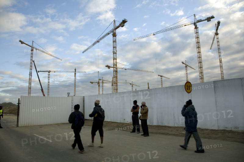 Workers arrive in the early morning to begin work on the new Greenpoint Stadium Seen from soccer fields in Greenpoint, construction cranes rise above the site of the new Greenpoint Stadium in Greenpoint, Cape Town. The all-weather stadium is designed to seat 70,000 people. The Stadium is one of 10 that will be used in the 2010 FIFA World Cup‚Ñ¢ / 2010 Soccer World Cup