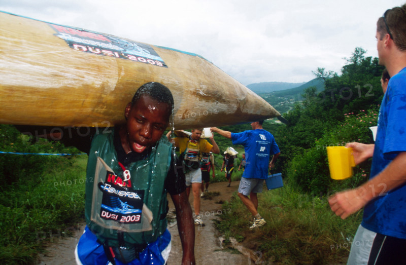 young black man covered in water walks just past the camera, guy