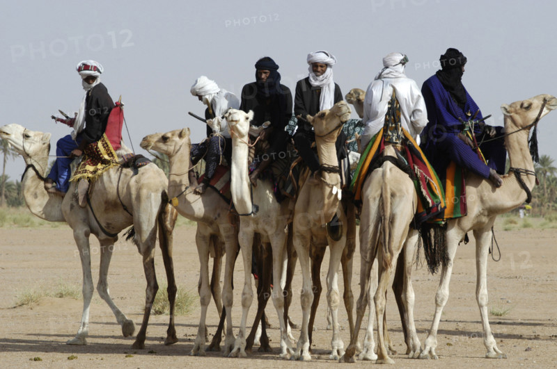 Nomads are seen on camels at the Salt Cure festival drawing nomads from all over the region to InGall, near Agadez in Niger on Thursday Sept. 25, 2003.  The Wodaabe men perform a dance, showing off the whiteness of their teeth and eyes, to compete for honour and selection as the most beautiful man by women of the tribe at the festival celebrated at the end of the rainy season. (Photo/Christine Nesbitt)