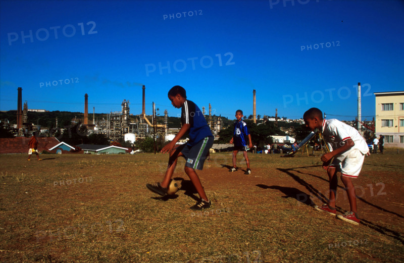 boys playing soccer with factories behind