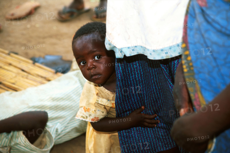 Child peers around mother
