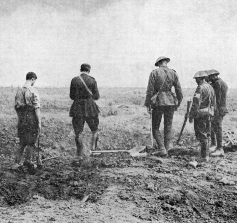 World War I: Army chaplain conducting burial service in the field while burial party stand, paying their respects
