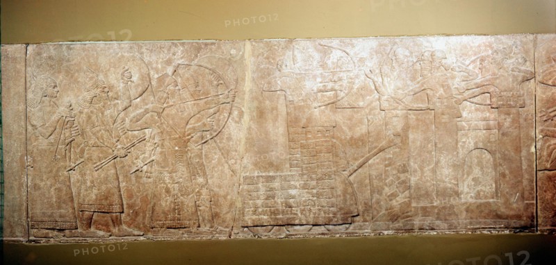 Ashurbanipal II, King of Assyria 833-859 BC, leading assault on city with battering rams and siege engines. Bas-relief. British Museum