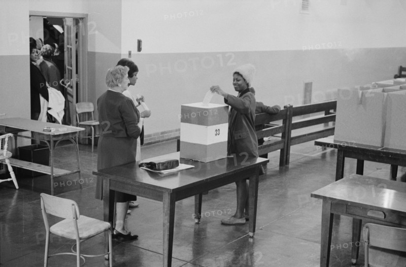 Young African American woman casting her vote in a ballot box