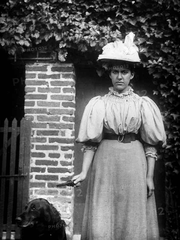 French woman stands next to a doorway with a dog