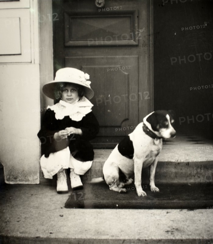 French girl photographed in a doorway with her pet dog, circa 1896