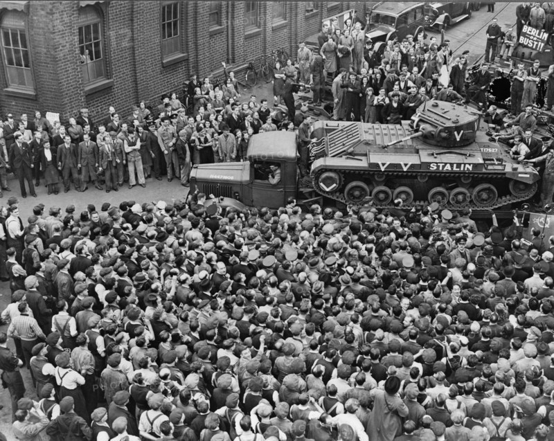 Crowds of people and a guard of honour of tanks