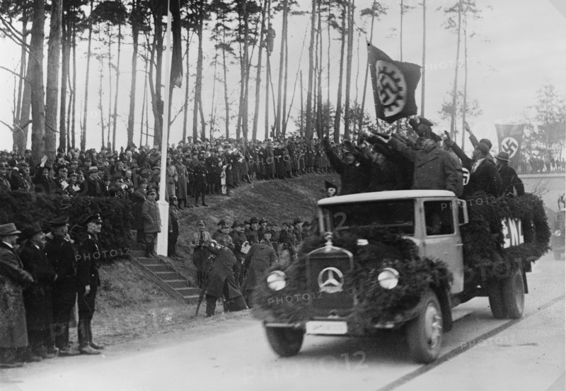 Men standing in the back of a truck salute Hermann Göring, 1936