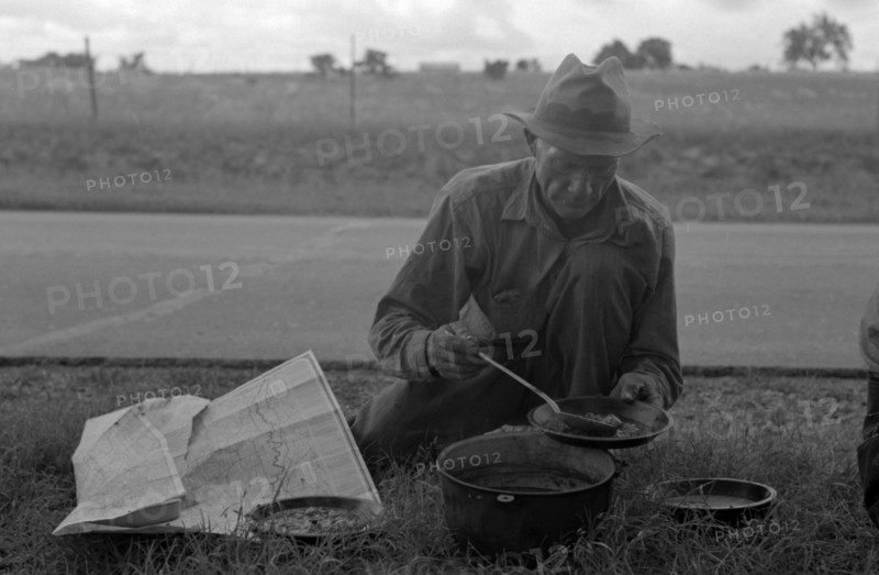 Migrant agricultural worker dishing up the noonday lunch of blackberry pie while camped by the roadside