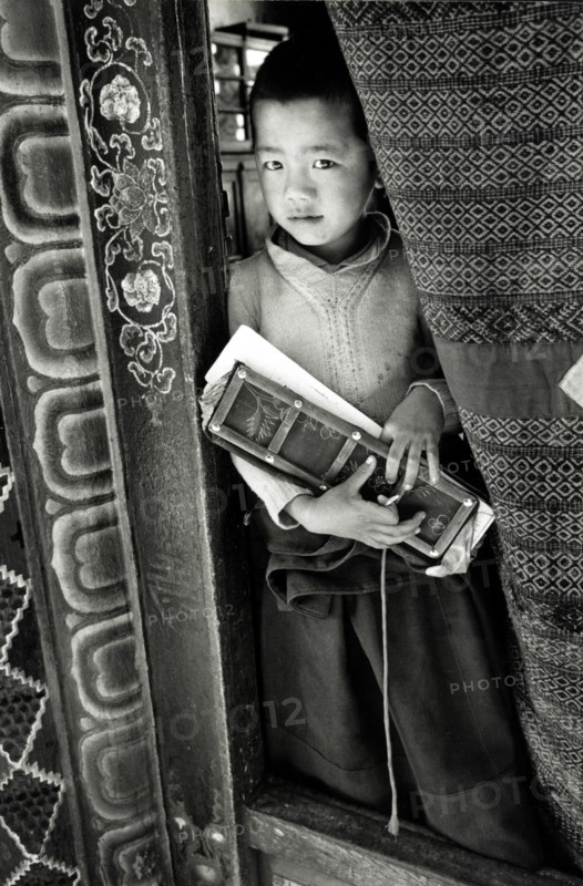 Photograph of a young boy holding a prayer book in Sikkim