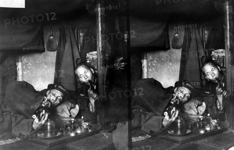 Two Chinese men, on narcotics in opium den.
