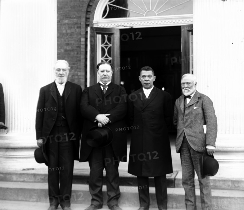 Robert C. Ogden, Senator William Howard Taft, Booker T. Washington and Andrew Carnegie, standing on the steps of a building, at the Tuskegee Institute