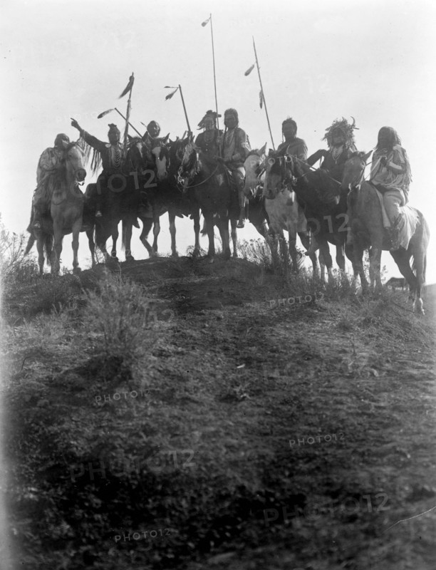 Photographic print of eight Crow Indians on horseback, silhouetted on top of hill