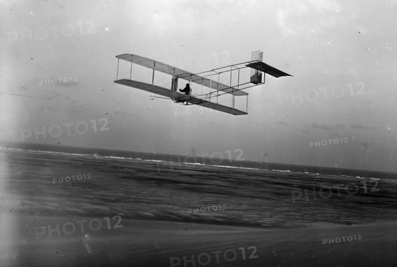 Three-quarter left rear view of glider in flight at Kitty Hawk