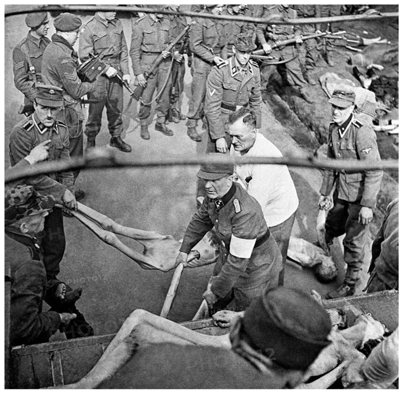 SS guards load victims of Bergen-Belsen concentration camp, into a trucks for burial, 1945