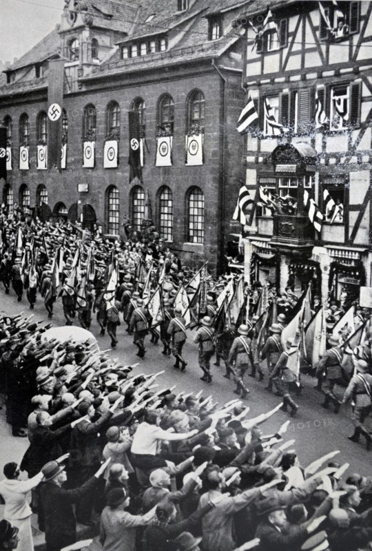 Armed forces Day in Nuremberg, 1935; Soldiers parade while onlookers give Nazi salute.