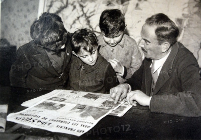 French family read newspaper outlining the liberation of towns in Alsace Lorraine 1944