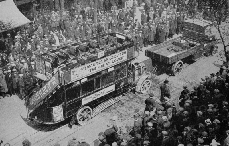 A crowd looks on as an early era London bus,1920