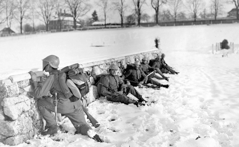 Swiss soldier in the snow peeking over a wall