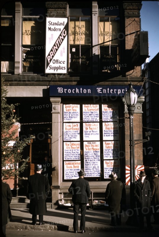 Men reading headlines posted in street-corner of Brockton Enterprise newspaper office