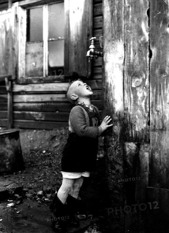 Photograph of a refugee boy drinking from a tap which is the sole source of water for the entire unofficial refugee camp known as Bahnhofstrasse