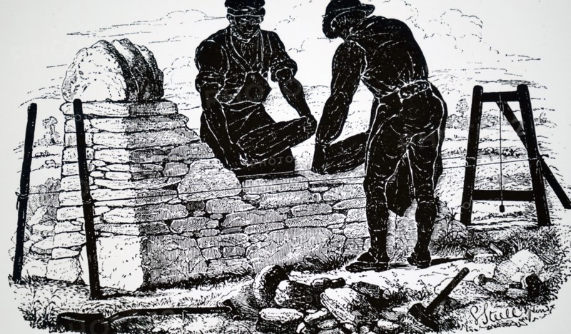 Two labourers building a dry stone wall somewhere in the English countryside