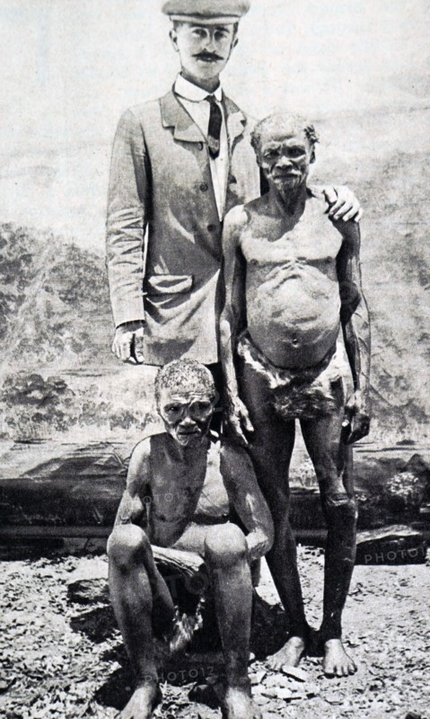 Photograph of a member of a pigmy tribe, standing with a European visitor