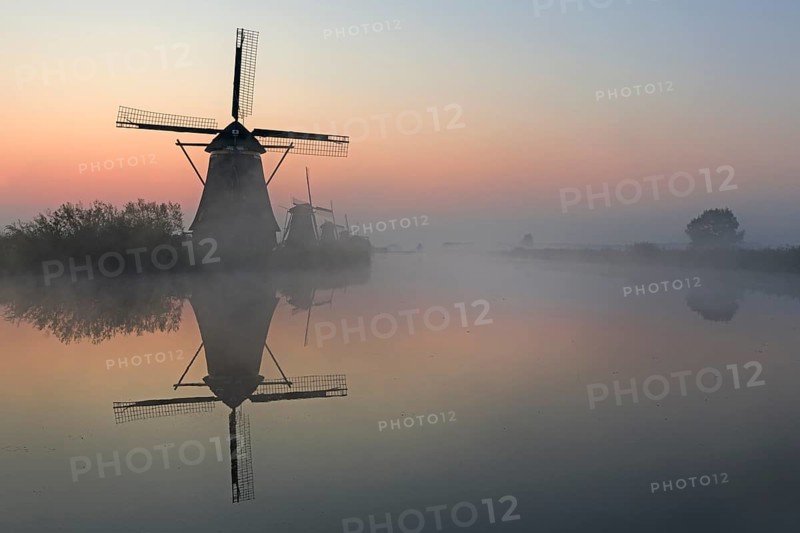 Historical windmills in the early morning fog at dawn