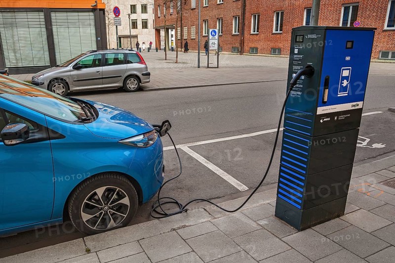Electric car is charged at green electricity charging station with charging cable