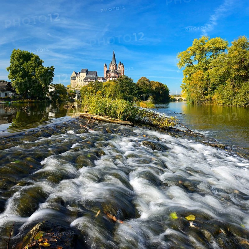 Limburg Cathedral St. Georg or Georgsdom and Limburg Castle over the river Lahn with weir in autumn