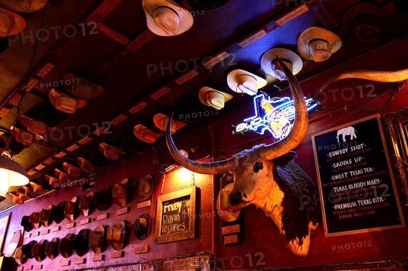 Wall with stuffed longhorn and many cowboy hats in a bar