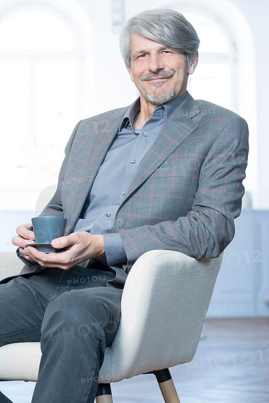 Man sits in his office chair with a coffee cup