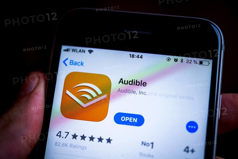 Hand holding an iPhone displaying the Audible app