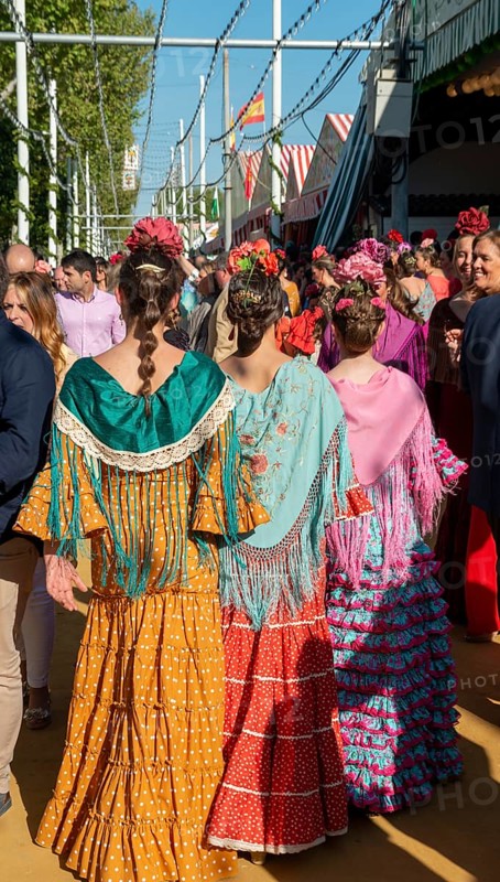Spanish women with colorful flamenco dresses in front of marquees