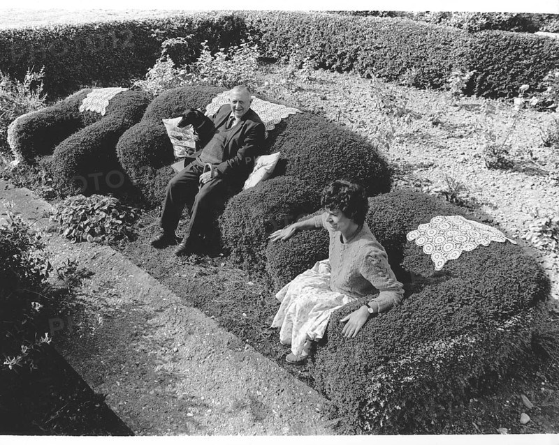 Old couple sitting on an armchair from a hedge