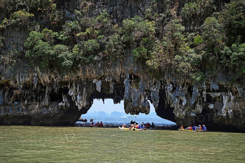 Tourists exploring eroded limestone rocks with canoes in Phang Nga Bay