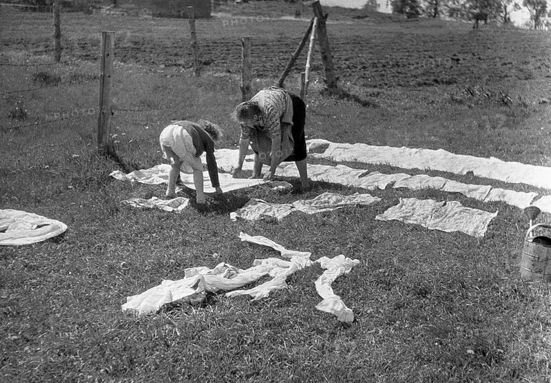 Mother and child put the laundry on the lawn and in the sun