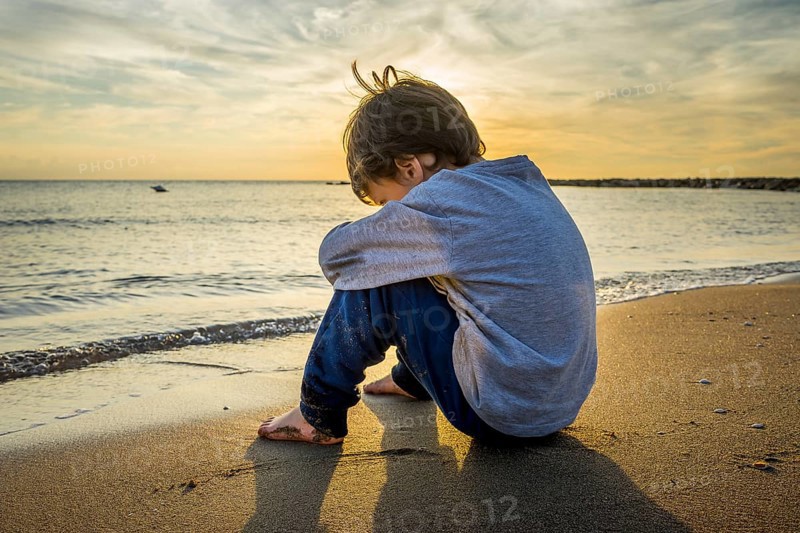 Sad boy sitting on the beach