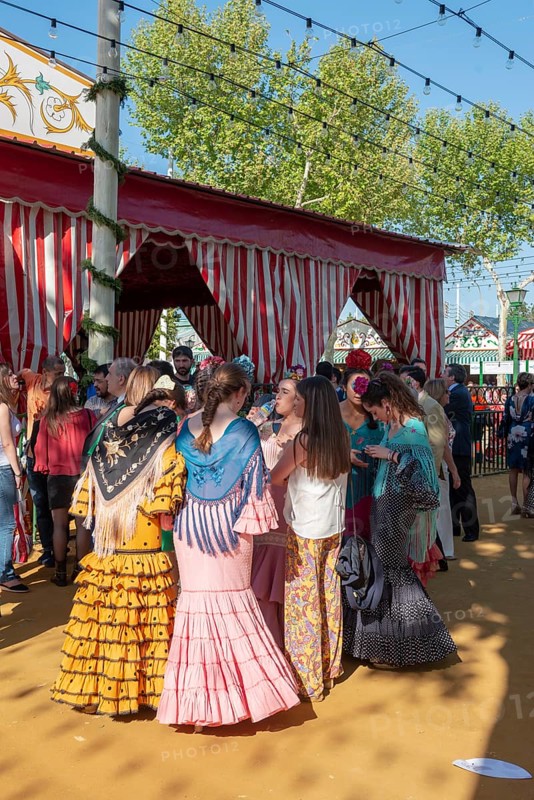 Spanish women with colorful flamenco dresses in front of marquees