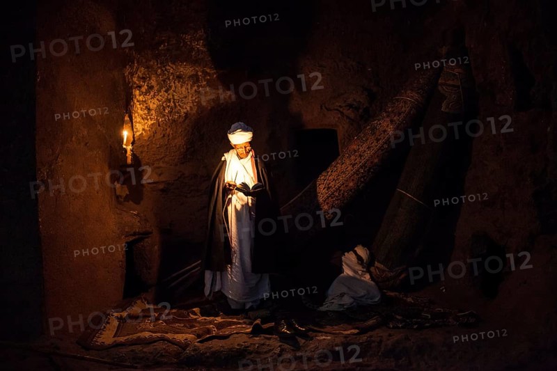Coptic priest by candlelight in Rock Church