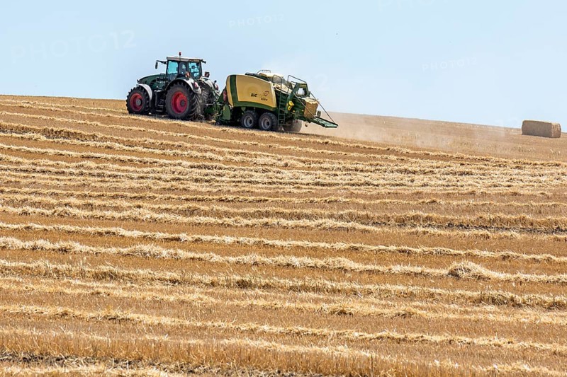 Tractor with straw baler on a mown wheat field
