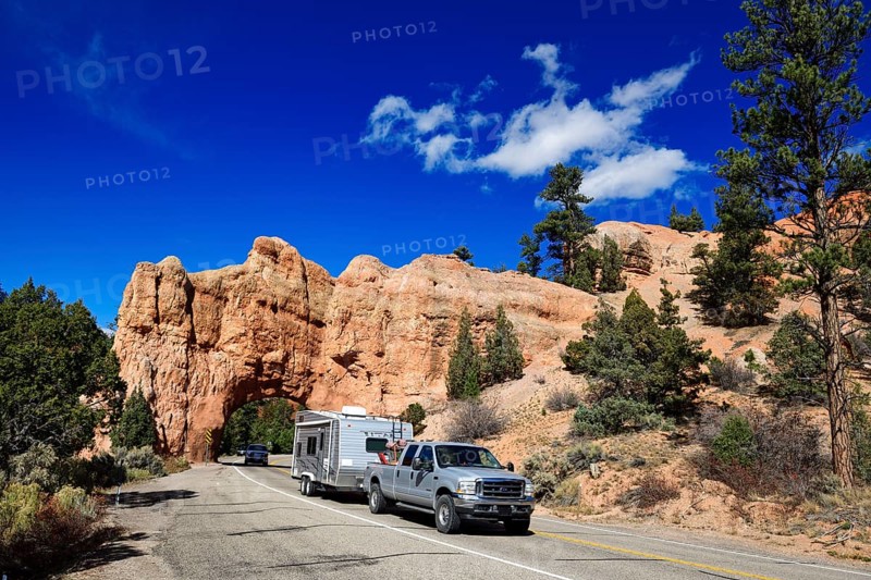 Pickup with caravan drives through a rock gate on Highway 12