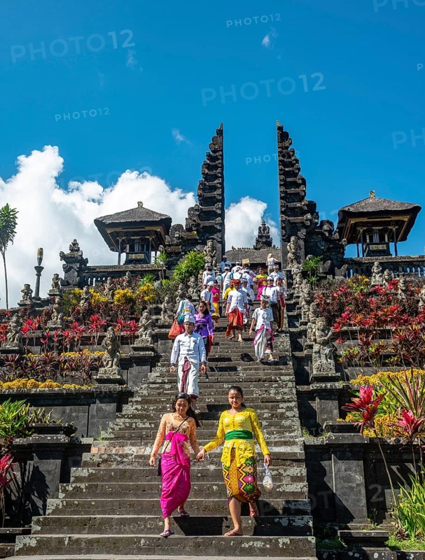 Balinese believers in traditional clothing go down stairs