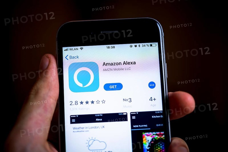 Hand holding iPhone with Amazon Alexa App in the Apple App Store