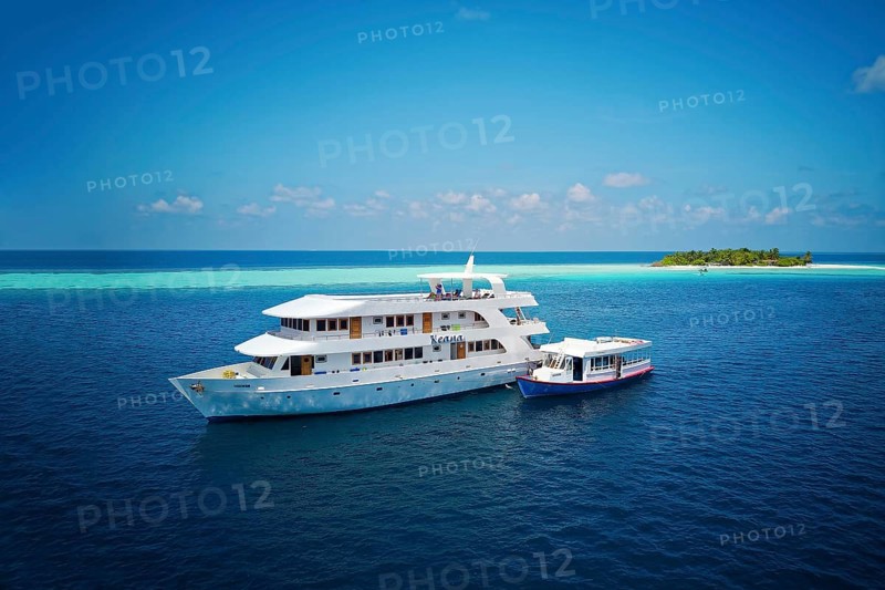 Diving safari ship MS Keana with diving dhoni anchored off an uninhabited palm island
