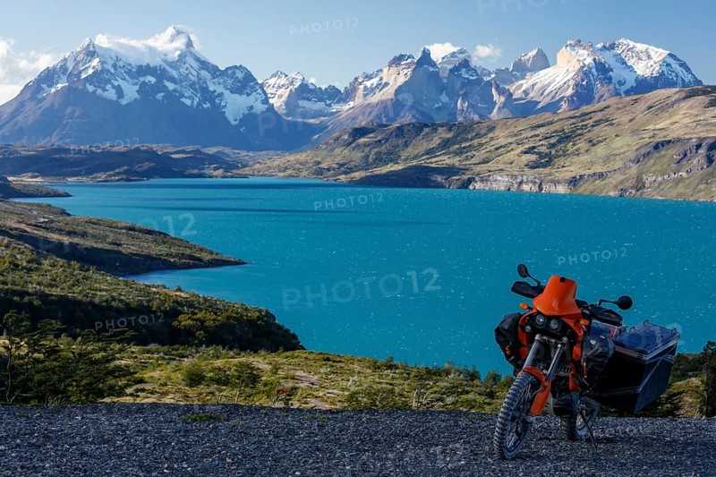 A heavily packed motorcycle on a gravel road behind the Lago del Torro and the mountain group Cordillera Paine