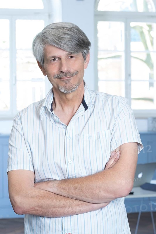 Man standing in his office with his arms crossed