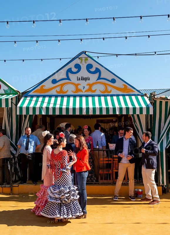 Spanish women with colorful flamenco dresses in front of marquees